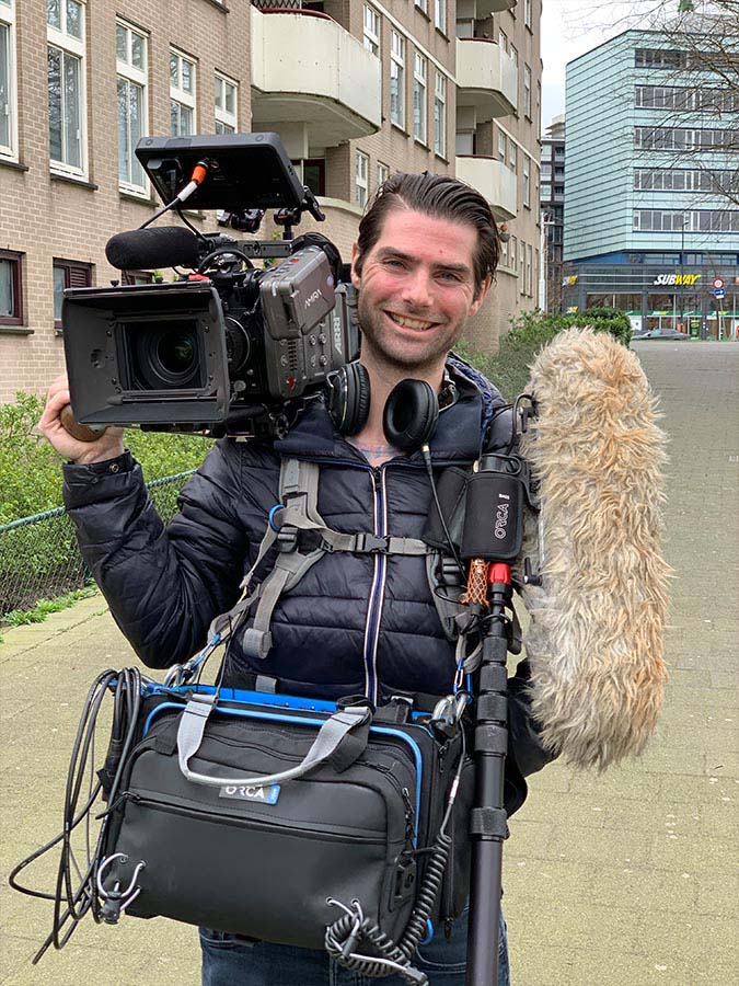 Michel Otjens met geluidsopname apparaat, microfoon en camera op de schouder